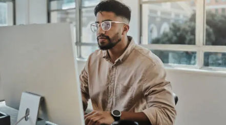 Marketer reviewing email campaign performance on a computer at a bright office desk